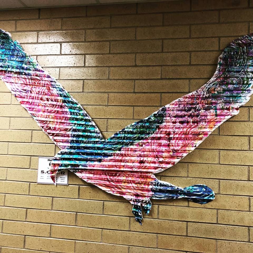 An image of a colorful eagle on a brick wall.