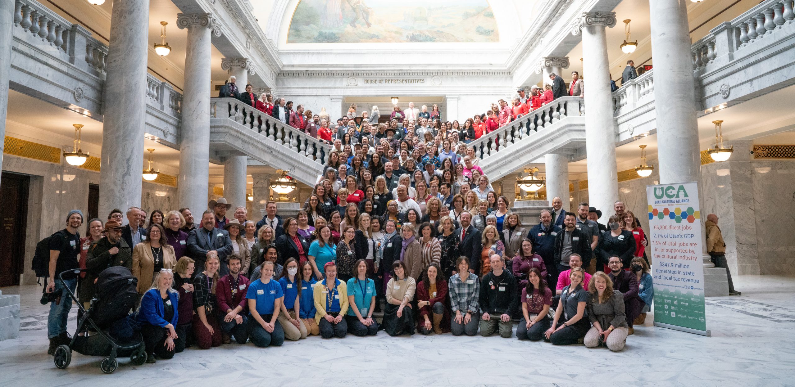 A large group of people smiles for the camera in the Utah State Capitol rotunda.